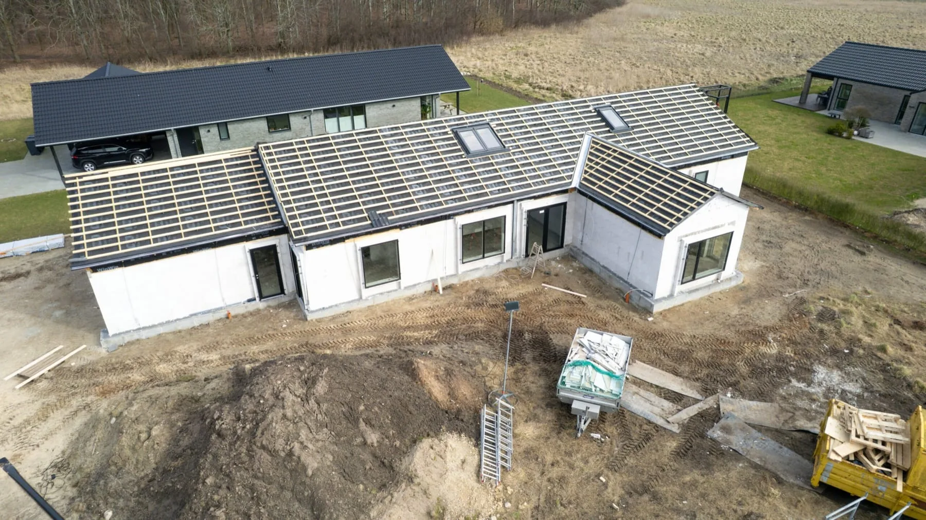 Nybygget hus set fra luften med byggeplads omkring